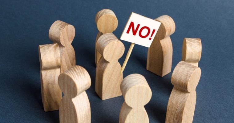 a series of wooden people in a circle with one in the middle holding a no sign
