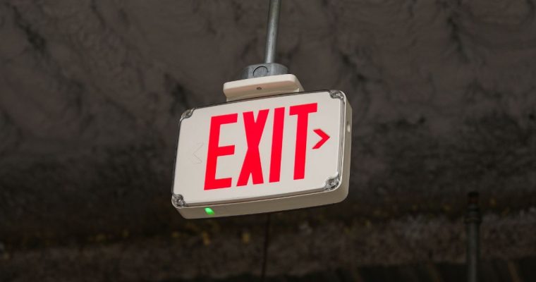 an exit sign hanging from a ceiling